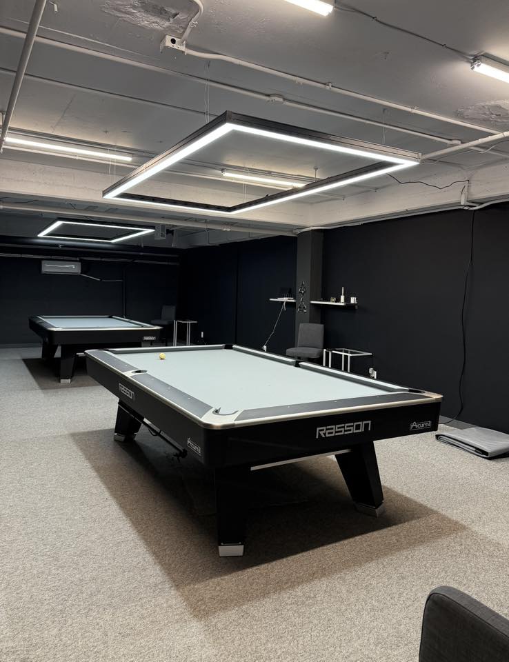 Pool table in a room with black walls and gray carpet